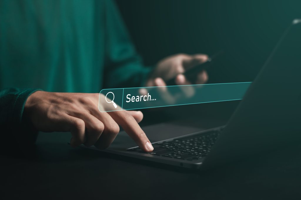 Person using a laptop with a search bar overlay, symbolizing SEO and content optimization.